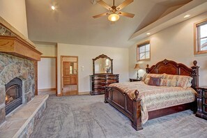 A spacious bedroom with a large bed, a fireplace, a ceiling fan, and a stone fireplace surround. - Massive Views, Affordable Luxury And Only 3 Miles To Main Street And Skiing (Breckenridge)