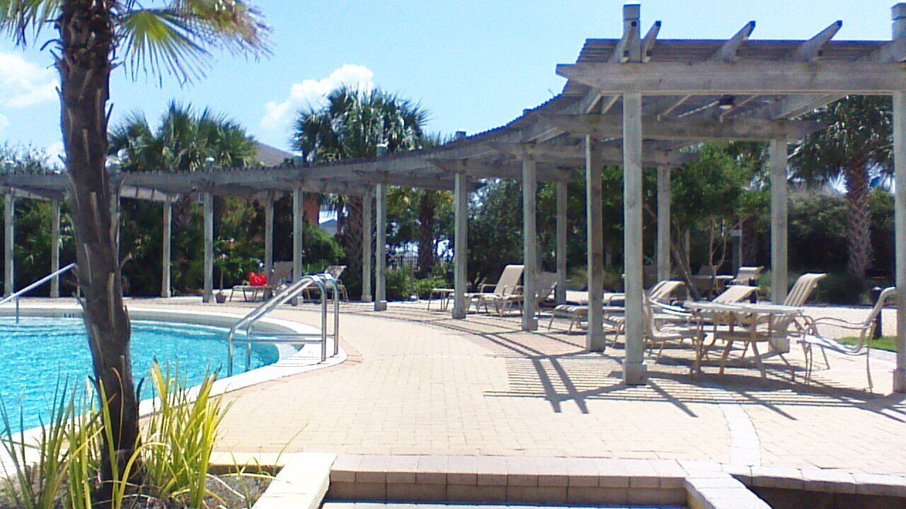 A pool area with lounge chairs and a pergola.