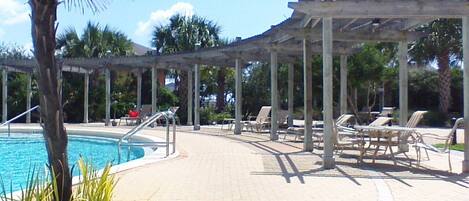 A pool area with lounge chairs and a pergola.