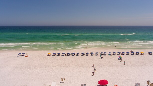 A beach with white sand and a clear blue sky. There are umbrellas and people on the beach. - Beautiful Beach View Condo!  1 Bedroom, Bunk room and 2 bath (Miramar Beach)