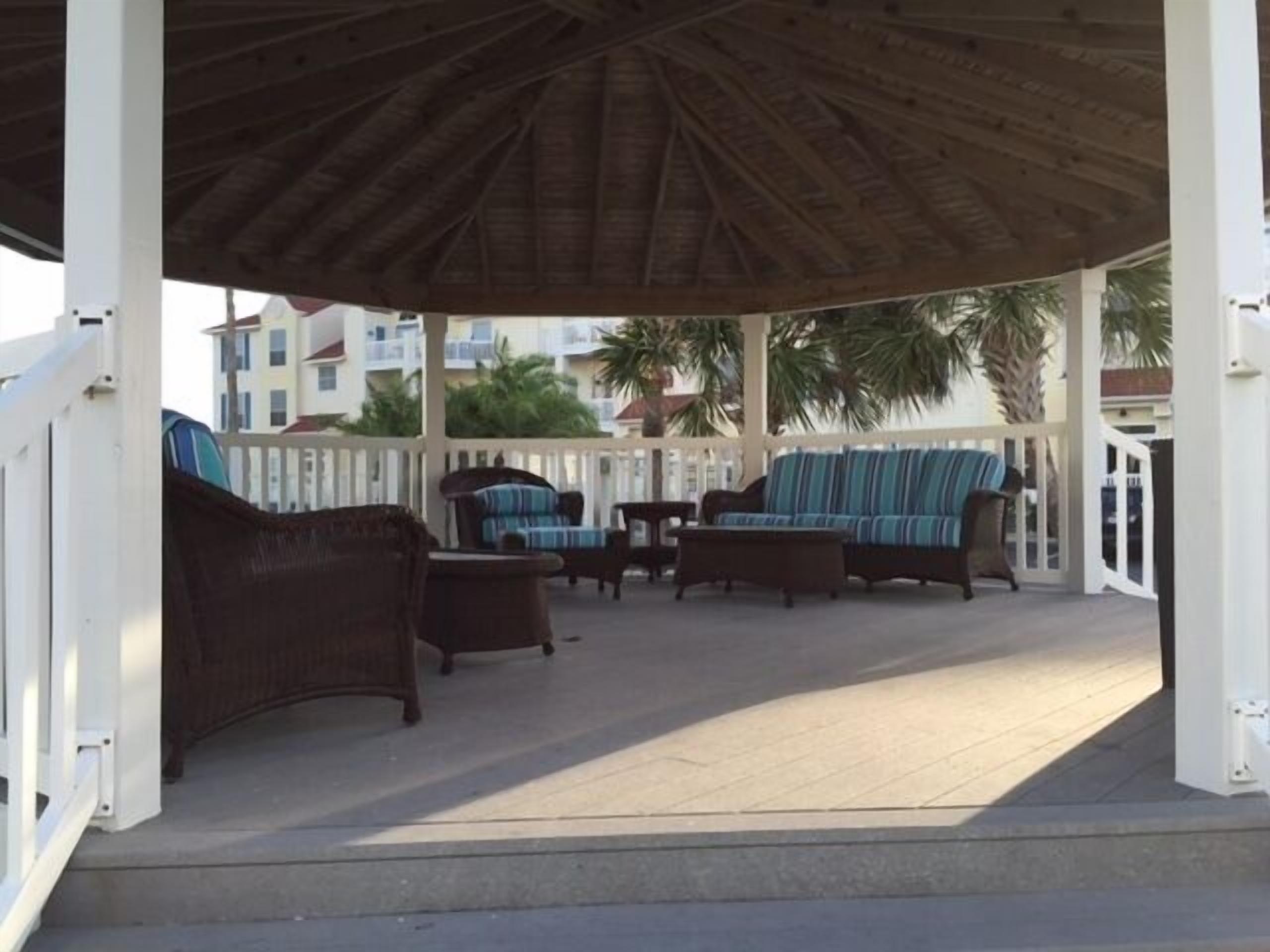 A covered outdoor seating area with wicker furniture and a striped sofa.