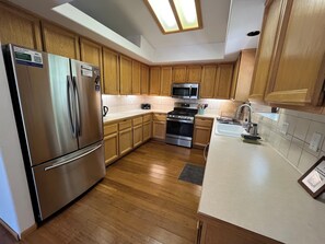 A modern kitchen with wooden cabinets, stainless steel appliances, a microwave, and a sink.