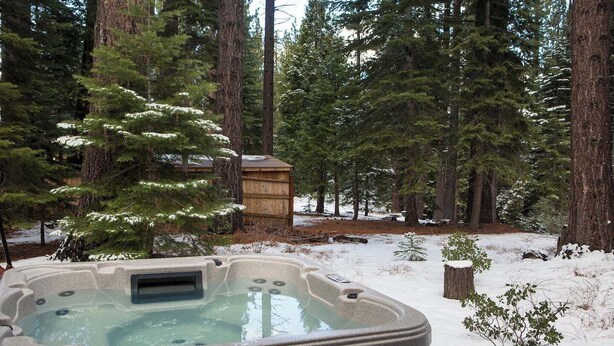Un bain à remous situé dans une zone boisée, avec de la neige au sol.