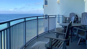 A balcony with a view of the ocean, furnished with wooden chairs and a table. - Sterling Breeze 1704! 2 Master Suites, Beachfront, Beach Chair Svc Incl! (Panama City Beach)