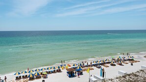 A beach with rows of sunbeds and umbrellas, a clear sky, and the ocean. - Sterling Breeze 1704! 2 Master Suites, Beachfront, Beach Chair Svc Incl! (Panama City Beach)