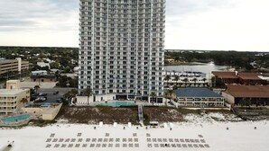 A high-rise hotel with multiple balconies, a swimming pool, and a beach area with sun loungers. - Sterling Breeze 1704! 2 Master Suites, Beachfront, Beach Chair Svc Incl! (Panama City Beach)