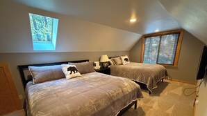Quarto com duas camas, janela com persianas, luminária no teto e televisão fixada na parede.