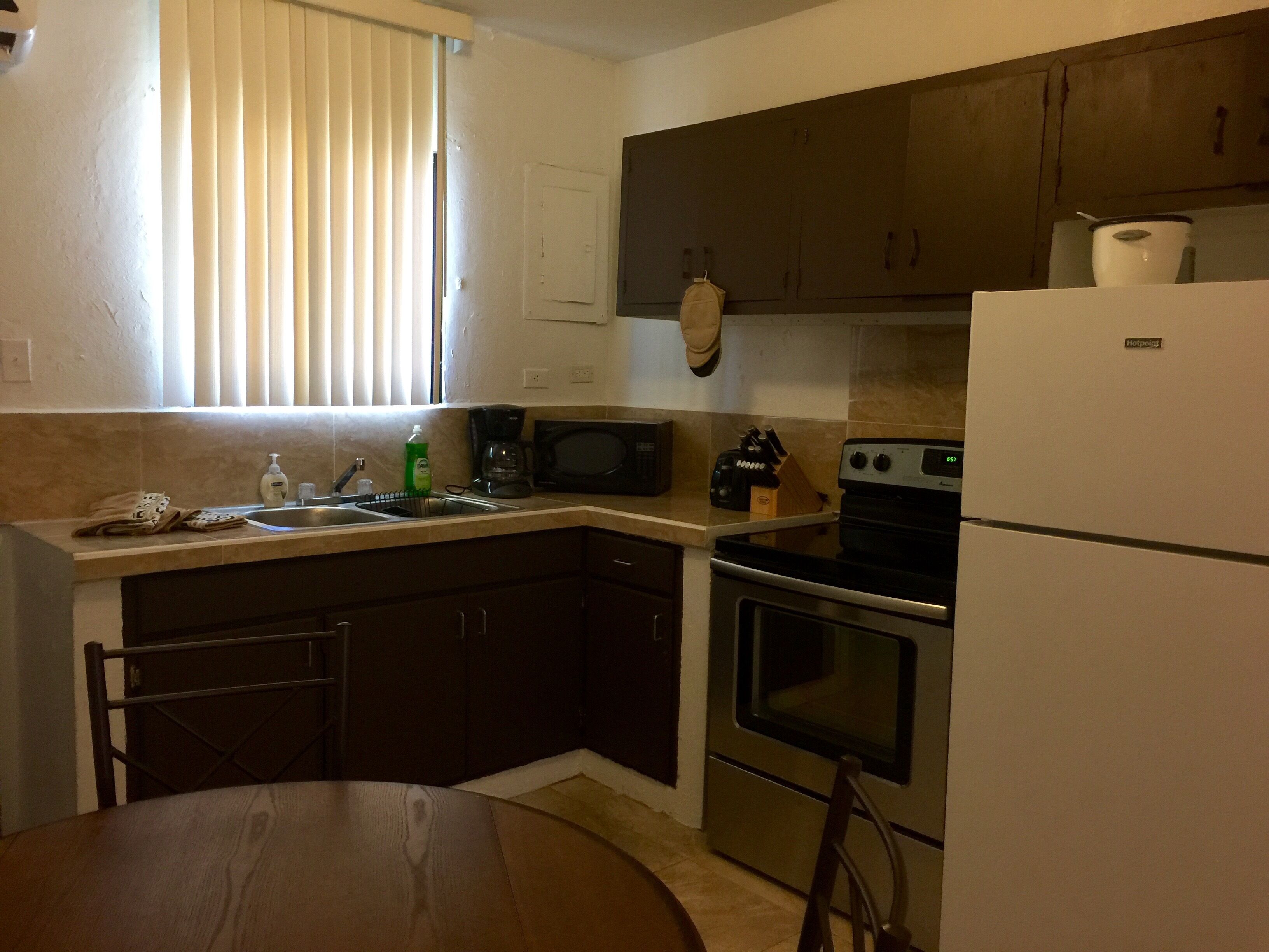 A compact kitchen with dark cabinets, a stainless steel stove, a microwave, and a refrigerator.
