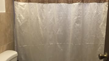 A bathroom with a white toilet, a beige sink, and a shower curtain with a brown and beige pattern.