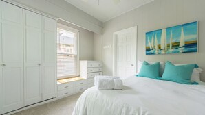 A bedroom with a large bed, white wardrobe, and a painting of sailboats. - Frances Cottage - Walking distance to downtown Saugatuck! Large backyard! (Saugatuck)