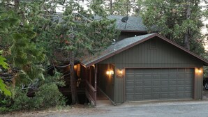Une cabane avec un garage, entourée d’arbres.