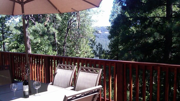 Une terrasse avec une table et des chaises, un parasol et une bouteille de vin.