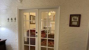 A room with a double door leading to another room, a bed with a beige cover, and a wall with a framed picture. - Spacious 1/1 apartment near Stetson, sky diving, river, springs, racing, beaches (Deland)