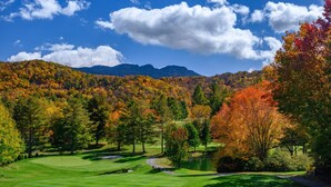 A golf course with a pond, surrounded by autumn-colored trees and mountains in the background. - Relaxing retreat on Otter Falls with views of Grandfather Mountain. (Seven Devils)