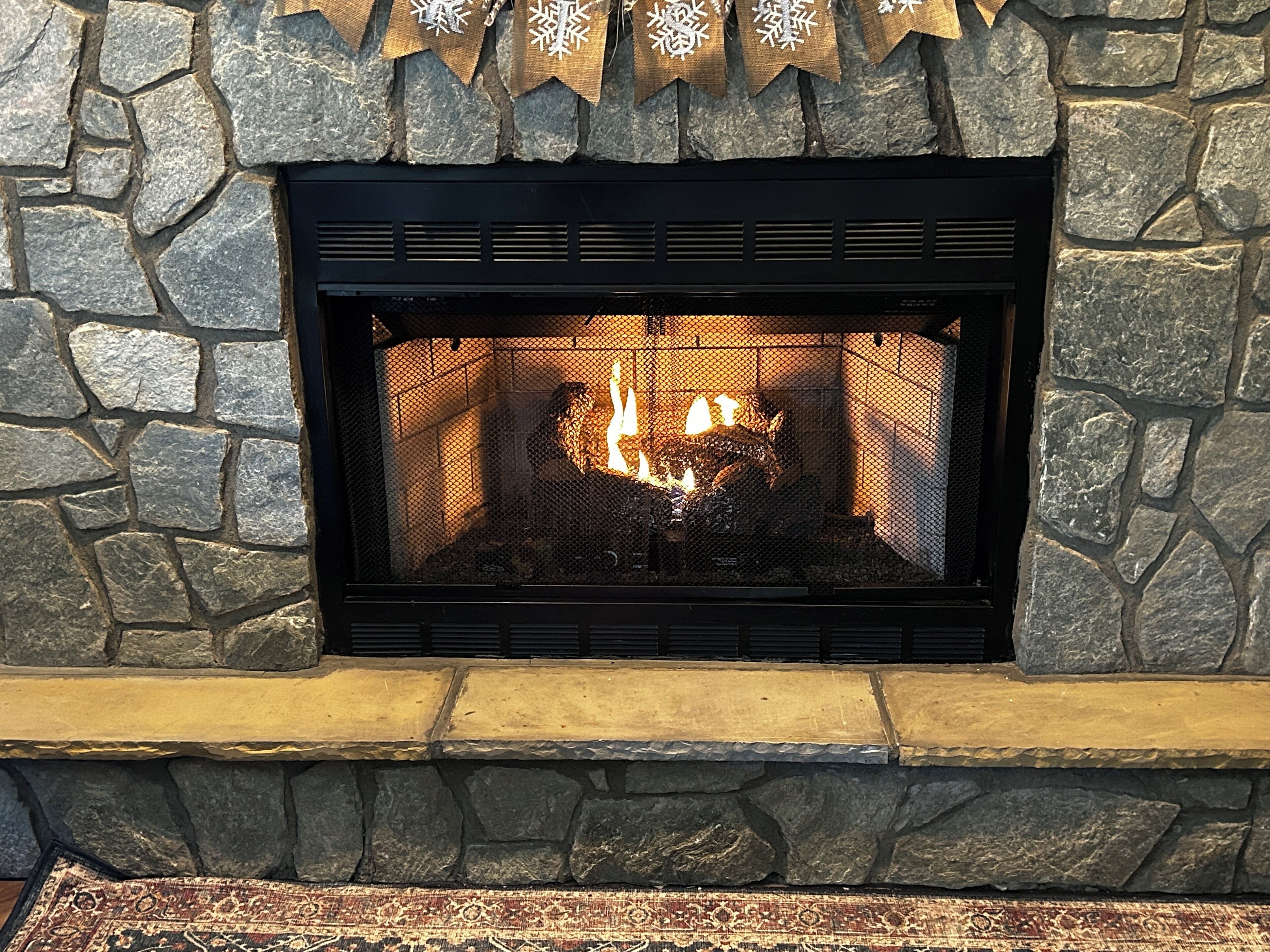 A stone fireplace with a fire burning inside.