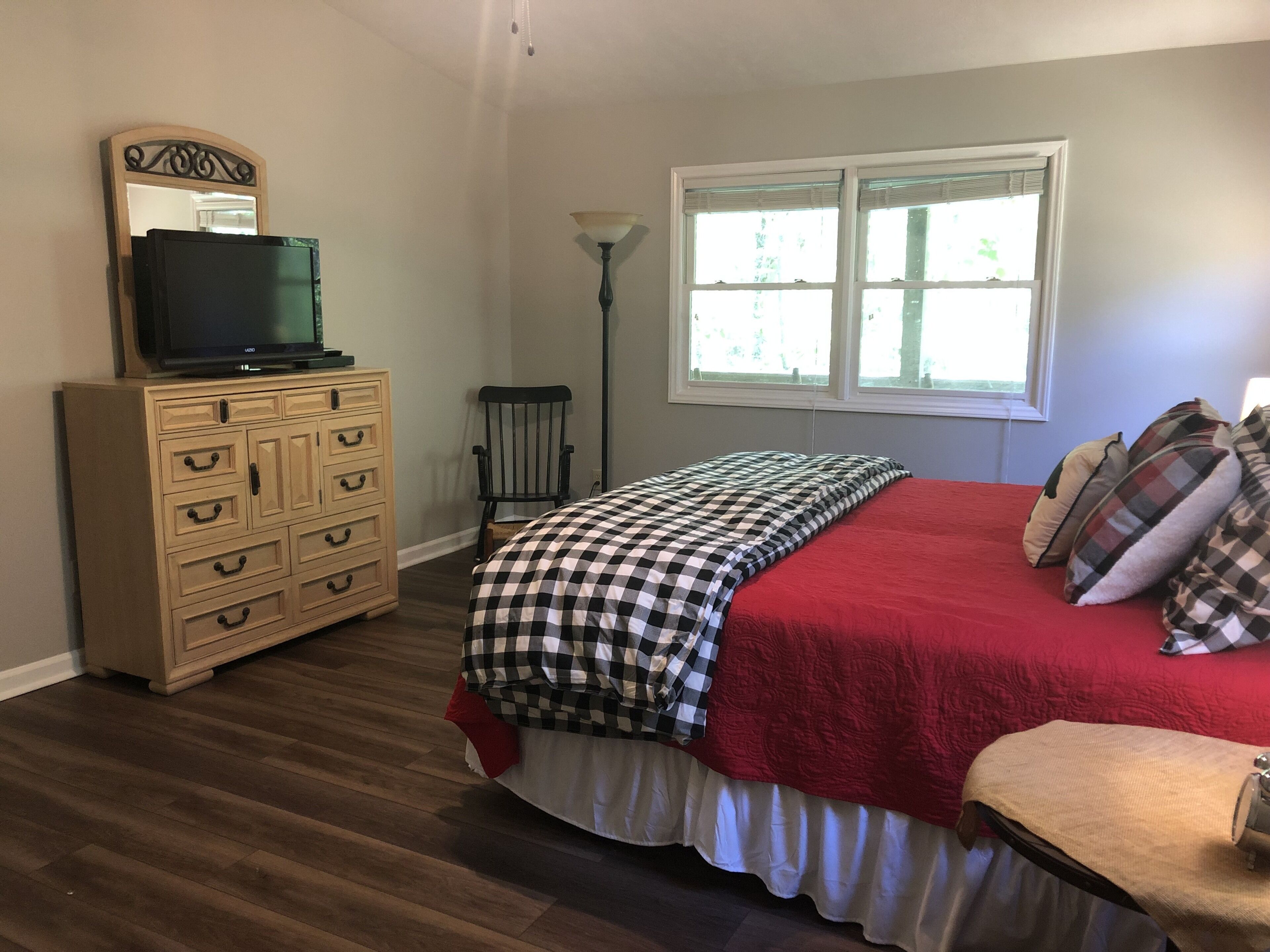 Um quarto com cama, cômoda e uma televisão sobre a cômoda.