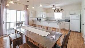 Una cocina moderna con armarios blancos, una mesa de comedor de madera y luces colgantes.