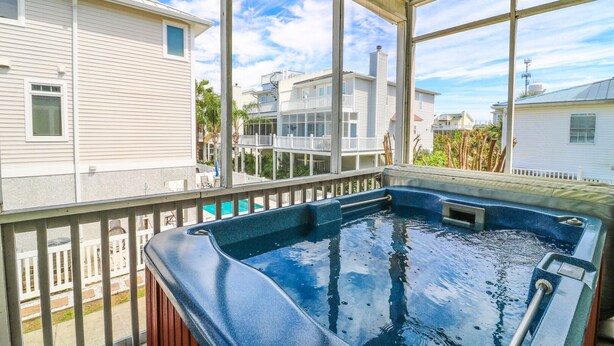 Un jacuzzi en un balcón con vistas a casas vecinas y un cielo despejado.