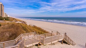 Ein Strand mit Holzstegen, die zum Ufer führen, feinem Sand und Meereswellen.