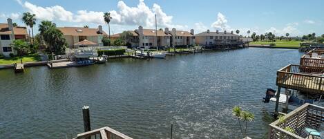 A marina with boats docked, a wooden deck, and a row of buildings with balconies.