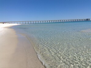 Ein Strand mit klarem, flachem Wasser und einer langen Seebrücke.
