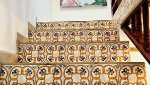 A staircase with ornate tile patterns and a painting of tropical flowers on the wall.