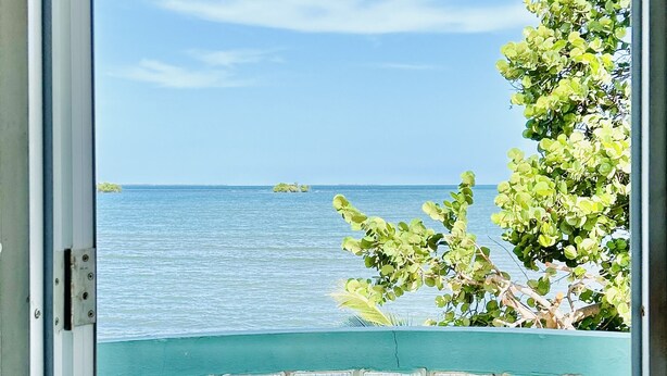 A view through a window with a view of the sea and a small island.