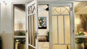 A building entrance with a glass door, a bench inside, and potted plants outside.