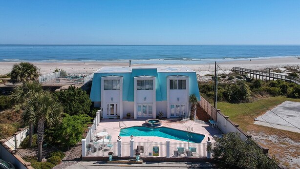 Een gebouw met twee verdiepingen, een zwembad en uitzicht op het strand.