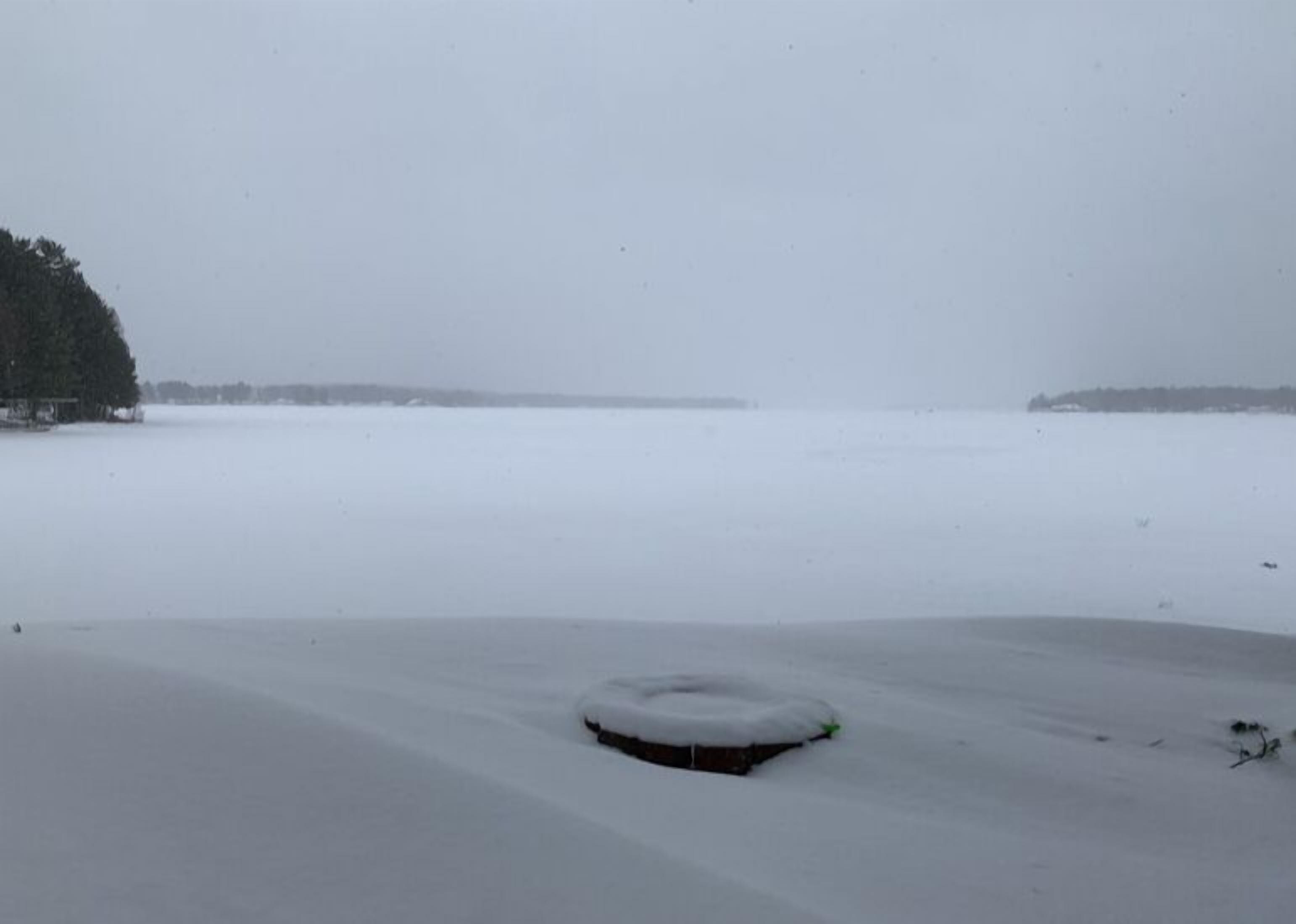 A snow-covered landscape with a body of water and a distant shoreline.