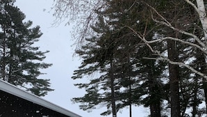 Lumipeitteinen polku johtaa puiseen rakennukseen, jossa on ikkuna ja ovi.