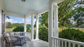 A covered porch with white columns, a sofa, and a table with chairs. - Private Paradise -  Historic 1870 Home on 630 Acre Estate - Pool, Lake, Views (Goochland)