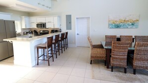 Una cocina moderna con armarios blancos, un refrigerador de acero inoxidable y una isla grande con taburetes de bar.
