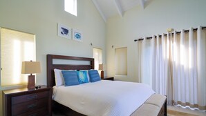 Un dormitorio con una cama grande, una mesita de noche con lámpara y una ventana con persianas.