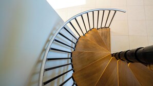 Una escalera de caracol con barandilla de madera y balaustradas de metal.