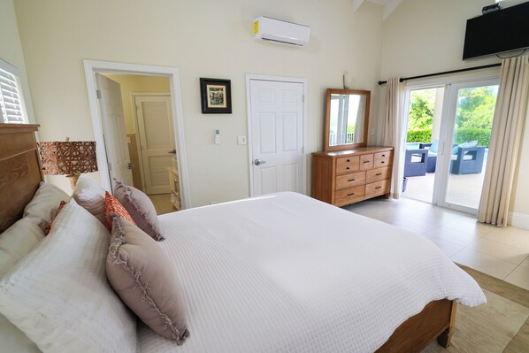 A bedroom with a bed, dresser, and a sliding glass door leading to a balcony.