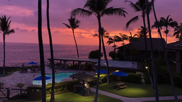 A resort with a pool area, palm trees, and a view of the ocean at sunset. - Oceanfront Paradise Kanaloa at Kona Condo
AC Stunning Ocean Views & Sunsets (Kailua-Kona)