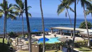 A pool area with lounge chairs, umbrellas, and a view of the ocean. - Oceanfront Paradise Kanaloa at Kona Condo
AC Stunning Ocean Views & Sunsets (Kailua-Kona)