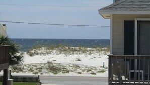 A two-story house with a balcony, a view of the beach, and a clear sky. - Hobbie's Hideaway - Fall Dates Available (Gulf Shores)