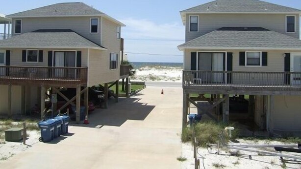 A beachfront property with two-story houses, a sandy beach in the background, and a clear sky. - Hobbie's Hideaway - Fall Dates Available (Gulf Shores)