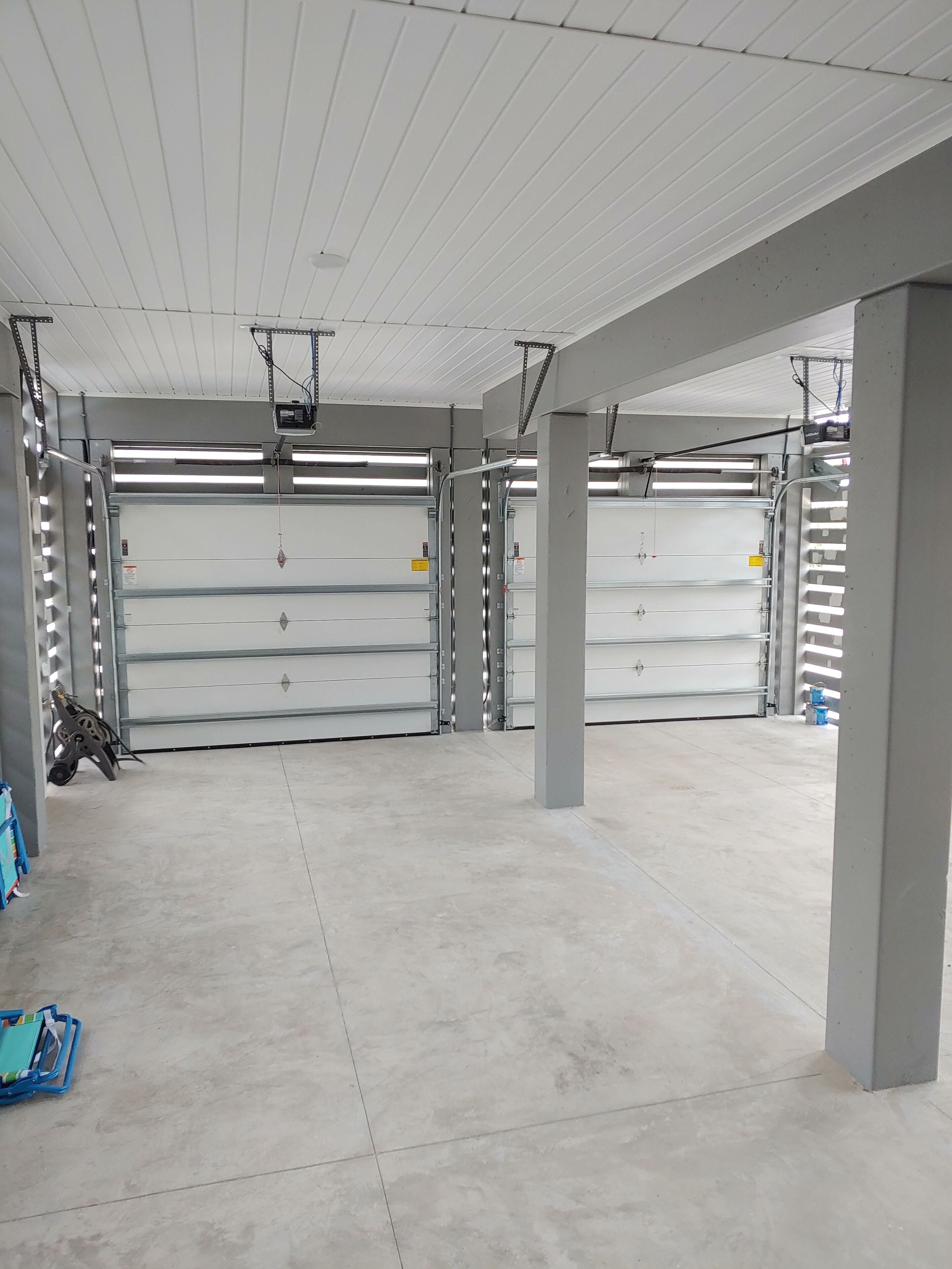 Ein großzügiger Innenparkbereich mit mehreren Garagentoren, Betonböden und Metallstützen.