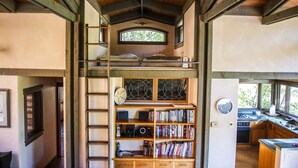 Een compact vakantiehuis met meerdere verdiepingen, een slaaploft, een bibliotheek en een keuken.