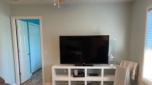 A living room with a flat-screen TV, a ceiling fan, and a white entertainment unit. - Quiet, Cozy, and Family Friendly in Hendo (Hendersonville)