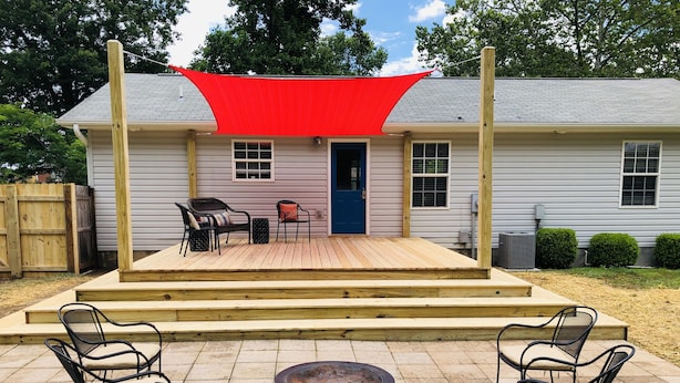 A house with a wooden deck, a red shade sail, and outdoor furniture including chairs and a table. - Quiet, Cozy, and Family Friendly in Hendo (Hendersonville)