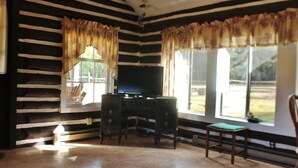 A room with a wooden slat wall, a desk with a television, and a chair. - "The Old Homestead"  An Original Homestead Cabin (Trout Creek)