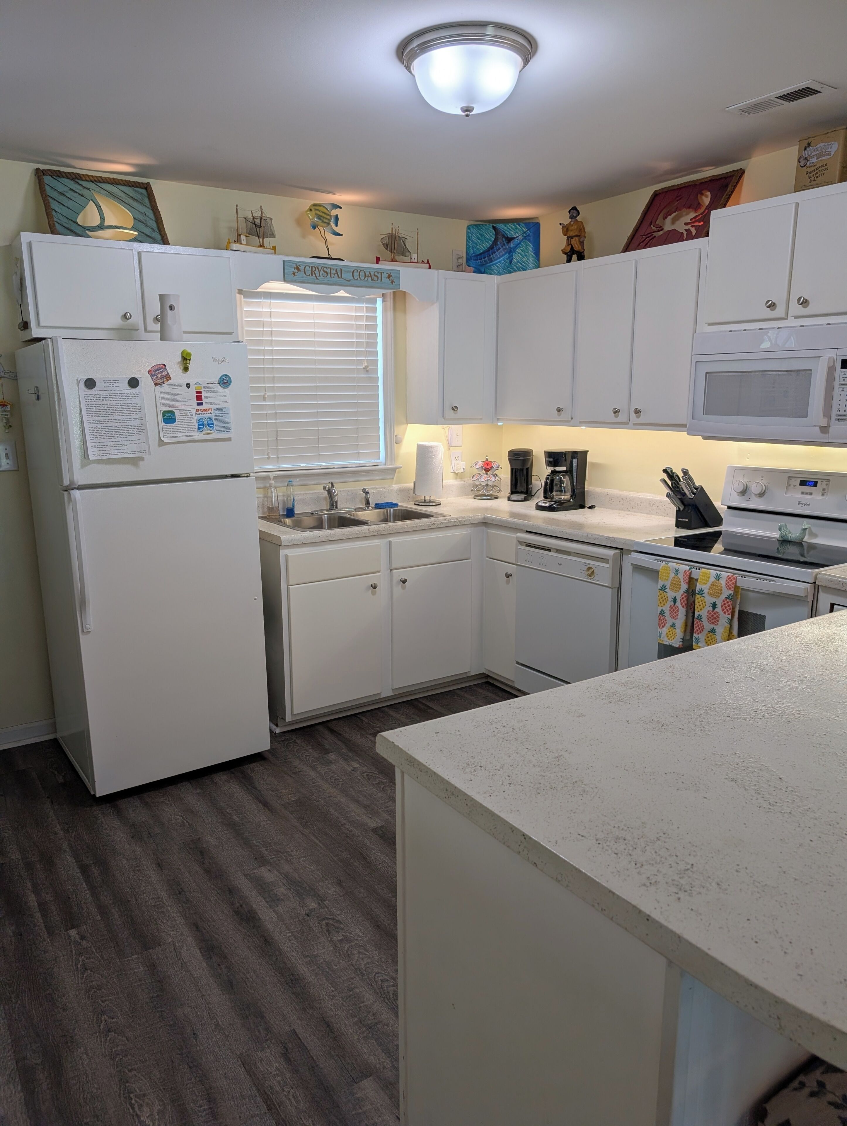 A kitchen with white cabinets, a refrigerator, a microwave, and a coffee maker.