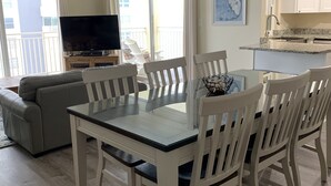 A dining area with a table and chairs, a television, and a balcony with a view. - Beautiful Beach! Spectacular Sunsets! (Redington Shores)