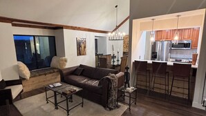 A spacious living room with a large sofa, a coffee table, and a TV. There is a kitchen area with a refrigerator and a microwave. -  PARK CITY CANYONS VILLAGE - LUXURY CONDO. ONE OF THE BEST LOCATIONS POSSIBLE, (Park City)