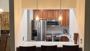 A modern kitchen with stainless steel appliances, wooden cabinets, and a central island with bar stools. -  PARK CITY CANYONS VILLAGE - LUXURY CONDO. ONE OF THE BEST LOCATIONS POSSIBLE, (Park City)