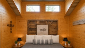 Ein Schlafzimmer mit einem Bett, zwei Nachttischen, einem Kruzifix, einem gerahmten Bild und einem Schild mit der Aufschrift 'Live. Laugh. Love.'.